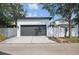 A detached two-car garage with a driveway, modern exterior lighting, and a white fence at 7307 S Trask St, Tampa, FL 33616