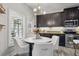 Eat-in kitchen featuring dark cabinetry, stainless steel appliances, a stylish chandelier, and natural light, perfect for dining at 7307 S Trask St, Tampa, FL 33616