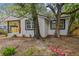 Exterior view of charming white home with dark trim, mature landscaping, and flowering plants at 8704 N Brooks St, Tampa, FL 33604