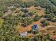 Aerial view of a property featuring a home with a pool, a barn, lush greenery, and a small pond, offering a private retreat at 8755 Ogleby Creek Rd, Myakka City, FL 34251