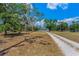 Gravel driveway leading to a light green home surrounded by lush trees and a well-maintained grassy lawn at 8755 Ogleby Creek Rd, Myakka City, FL 34251