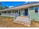 Inviting front entrance with a wraparound porch and well-maintained steps leading to a blue door at 8755 Ogleby Creek Rd, Myakka City, FL 34251