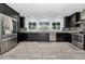 Modern kitchen featuring black cabinets, stainless steel appliances, and a view through large windows at 8755 Ogleby Creek Rd, Myakka City, FL 34251