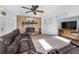 Comfortable living room with stone fireplace, ceiling fan, and a view of the backyard at 8755 Ogleby Creek Rd, Myakka City, FL 34251
