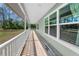 Spacious covered porch with wooden flooring, providing a perfect spot for outdoor relaxation at 8755 Ogleby Creek Rd, Myakka City, FL 34251