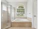 Bright bathroom with a large tub, separate glass shower and arched window at 9422 Clover Glen Dr, Riverview, FL 33569