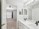 Modern bathroom with double sinks, white cabinets, black hardware and a large mirror at 9422 Clover Glen Dr, Riverview, FL 33569