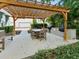 A wooden pergola with outdoor dining table and grill, surrounded by lush green landscaping at 946 Highland Ave # 24, Dunedin, FL 34698