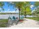 Lakeside backyard with palm trees and Adirondack chairs around a fire pit offers a relaxing outdoor space at 9818 Tree Tops Lake Rd, Tampa, FL 33626