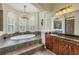 Bathroom with an elevated tub and elegant chandelier next to arched windows with plantation shutters at 9818 Tree Tops Lake Rd, Tampa, FL 33626