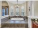 Large soaking tub on a raised platform in a bathroom with three arched windows and a chandelier at 9818 Tree Tops Lake Rd, Tampa, FL 33626