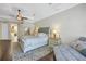 Cozy bedroom with a king bed, hardwood floors, ceiling fan, sitting area, and ensuite bath at 9818 Tree Tops Lake Rd, Tampa, FL 33626