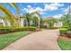 Stunning Mediterranean-style home with lush landscaping, a brick driveway and a barrel tile roof at 9818 Tree Tops Lake Rd, Tampa, FL 33626