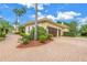 Side view of home featuring a two car garage, lush landscaping and a brick driveway at 9818 Tree Tops Lake Rd, Tampa, FL 33626