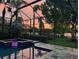 Beautiful pool and spa at sunset enclosed in a screen, surrounded by lush landscaping at 9818 Tree Tops Lake Rd, Tampa, FL 33626