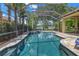 Gorgeous screened-in pool and spa area with serene water views, surrounded by tropical landscaping at 9818 Tree Tops Lake Rd, Tampa, FL 33626