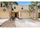 Inviting townhouse exterior featuring a one-car garage, palm trees, and manicured landscaping at 9960 Hound Chase Dr, Gibsonton, FL 33534