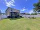 A large backyard with green grass, a patio, a fire pit, and a white fence at 11013 Leland Groves Dr, Riverview, FL 33579