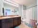 Well-lit bathroom with double vanity, dark wood cabinets, and shower/tub combo with stylish curtains, offering a functional design at 11013 Leland Groves Dr, Riverview, FL 33579