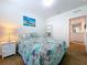 Cozy bedroom with a colorful seashell-themed quilt and a tranquil beach-themed artwork at 11013 Leland Groves Dr, Riverview, FL 33579