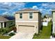 Beige two-story home with two-car garage and well-manicured landscaping in a sunny neighborhood at 11013 Leland Groves Dr, Riverview, FL 33579