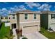 Two-story home with a beige exterior, two-car garage, manicured landscaping, and a blue sky above at 11013 Leland Groves Dr, Riverview, FL 33579