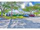 Exterior shot of the condo, featuring trees, lush landscaping, and a parking area with two cars at 11200 102Nd Ave # 75, Seminole, FL 33778