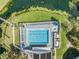 Aerial view of a community pool with lounge chairs and sun umbrellas, set amidst lush greenery and a tranquil pond at 11440 Harbor Way # 5009, Largo, FL 33774