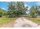 A view of the dirt driveway, surrounded by mature trees and natural landscape at 12009 Glenshire Dr, Riverview, FL 33579