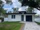 Beautiful single Gathering home with a white exterior, black trim, a modern garage door, and manicured lawn at 12308 Pittsfield Ave, Tampa, FL 33624