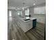 Open kitchen and living room area, featuring white kitchen cabinets, a center island, and stainless steel appliances at 12308 Pittsfield Ave, Tampa, FL 33624