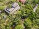Aerial view of home surrounded by lush greenery and a water feature at 1296 Weybridge Ln, Dunedin, FL 34698