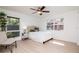 Bright bedroom featuring a cozy bed, light wood flooring, a bedside table, and views of the trees outside at 1296 Weybridge Ln, Dunedin, FL 34698