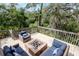 Outdoor deck featuring wood flooring, a brick fire pit, and wicker seating surrounded by lush trees at 1296 Weybridge Ln, Dunedin, FL 34698