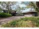 Home exterior with a brick driveway surrounded by lush landscaping and mature trees at 1296 Weybridge Ln, Dunedin, FL 34698