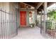Inviting front porch with a bright red door framed by wrought iron and views of verdant foliage at 1296 Weybridge Ln, Dunedin, FL 34698