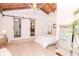 Bright main bedroom featuring high vaulted ceilings, wood beams, sliding barn doors, and elegant light fixtures at 1296 Weybridge Ln, Dunedin, FL 34698