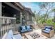 Outdoor deck featuring wicker patio furniture, a brick fire pit, wooden railings, and a lush view of the tree canopy at 1296 Weybridge Ln, Dunedin, FL 34698