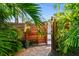 Private wooden gate leading to a lush tropical paradise with brick pavers at 135 12Th Ne Ave, St Petersburg, FL 33701