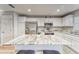 A kitchen island with barstool seating in a modern kitchen with white cabinets and stainless steel appliances at 13822 Harvestwood Ln, Riverview, FL 33569