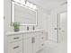 Bathroom features illuminated mirror, white cabinets with black hardware and stone floors at 13934 Clubhouse Cir # 8, Tampa, FL 33618