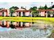 Exterior community view with pink stucco homes reflecting in a pond with lush landscaping at 141 Lakeside Dr, Oldsmar, FL 34677