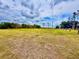 Expansive plot of land under a cloudy sky, featuring grassy terrain and distant power lines at 141 Lakeside Dr, Oldsmar, FL 34677