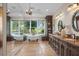 Luxurious bathroom with dual vanities, soaking tub, travertine floors, and backyard views at 17129 Breeders Cup Dr, Odessa, FL 33556