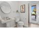 Elegant bathroom with a pedestal sink, decorative mirror, and access to the patio at 17129 Breeders Cup Dr, Odessa, FL 33556