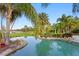 An inviting backyard pool with lush tropical landscaping, set against a beautiful backdrop of water and green space at 17129 Breeders Cup Dr, Odessa, FL 33556