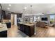 A kitchen flows seamlessly into living room with granite counters, dark cabinets, stainless appliances and pendant lighting at 1726 Hadden Hall Pl, Trinity, FL 34655