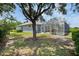 Landscaped backyard featuring mature trees, a screen-enclosed pool area, and a well-maintained lawn at 18107 Sugar Brooke Dr, Tampa, FL 33647