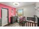 Pink accent wall in bedroom with grey floors, a window, closet, and crib at 2122 W Ferris Ave, Tampa, FL 33603