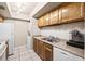 Functional kitchen features wood cabinetry, neutral countertops, and a stainless steel sink with tiled backsplash at 2597 Countryside Blvd # 206, Clearwater, FL 33761